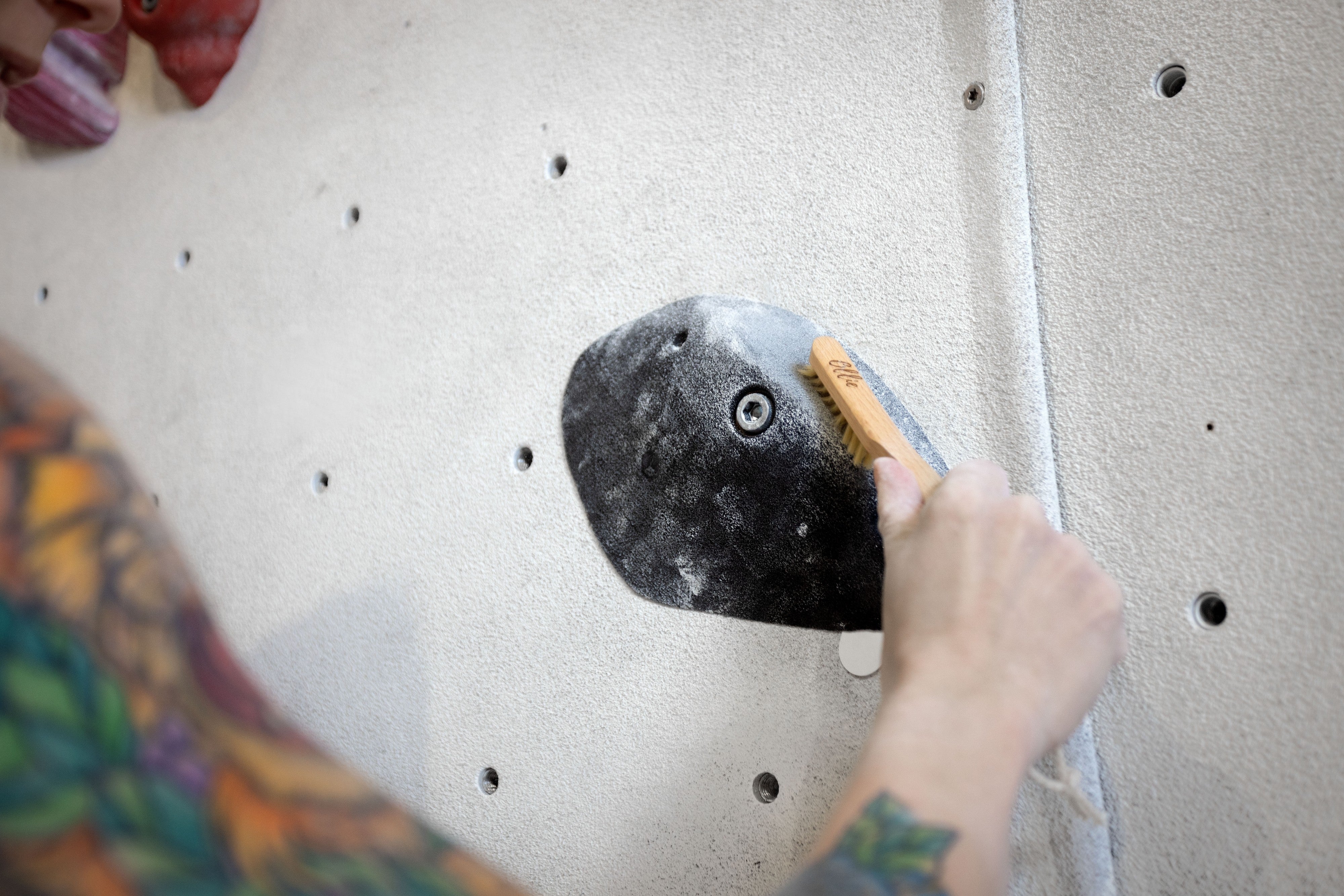 Cleaning a climbing hold with a bouldering brush